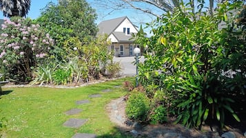 A garden pathway leading to a house with a well-maintained lawn and various plants.
