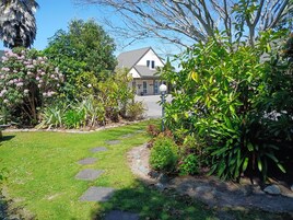 A garden pathway leading to a house with a well-maintained lawn and various plants.