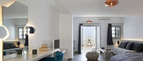 Une chambre moderne avec un grand lit, un bureau avec une chaise, un miroir et une vue sur l’extérieur.