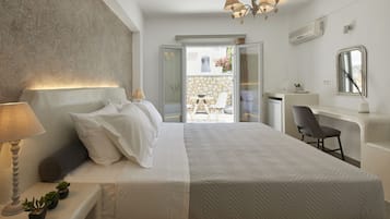 A modern bedroom with a large bed, bedside table with a lamp, and a view of an outdoor patio.