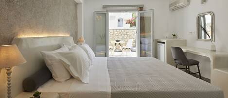 Un dormitorio moderno con una cama grande, mesita de noche con lámpara y vista a un patio exterior.