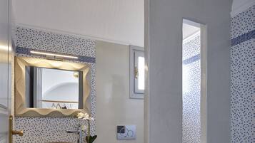 Un baño moderno con un lavabo sobre encimera, un espejo grande y una lámpara en el techo.