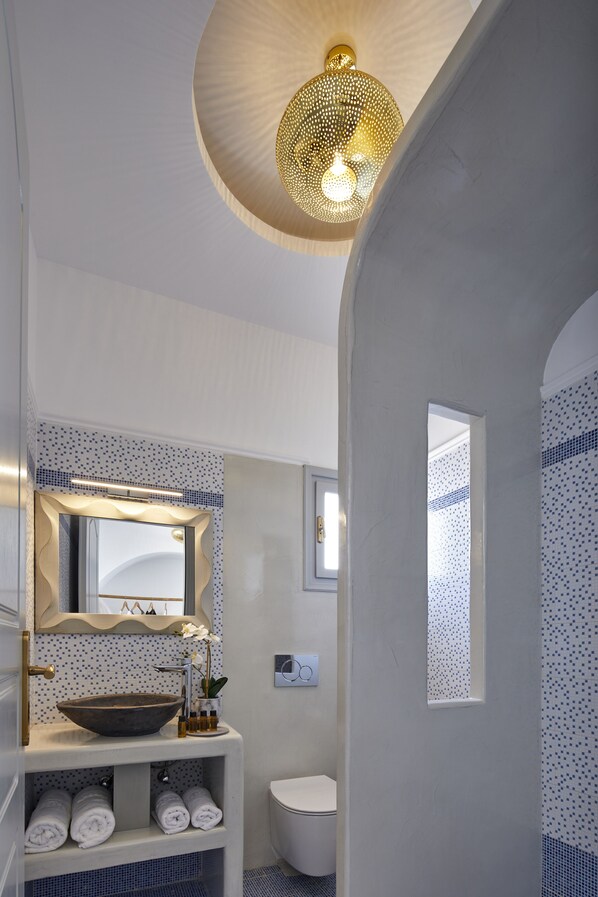 A modern bathroom with a vessel sink, a large mirror, and a ceiling light fixture.