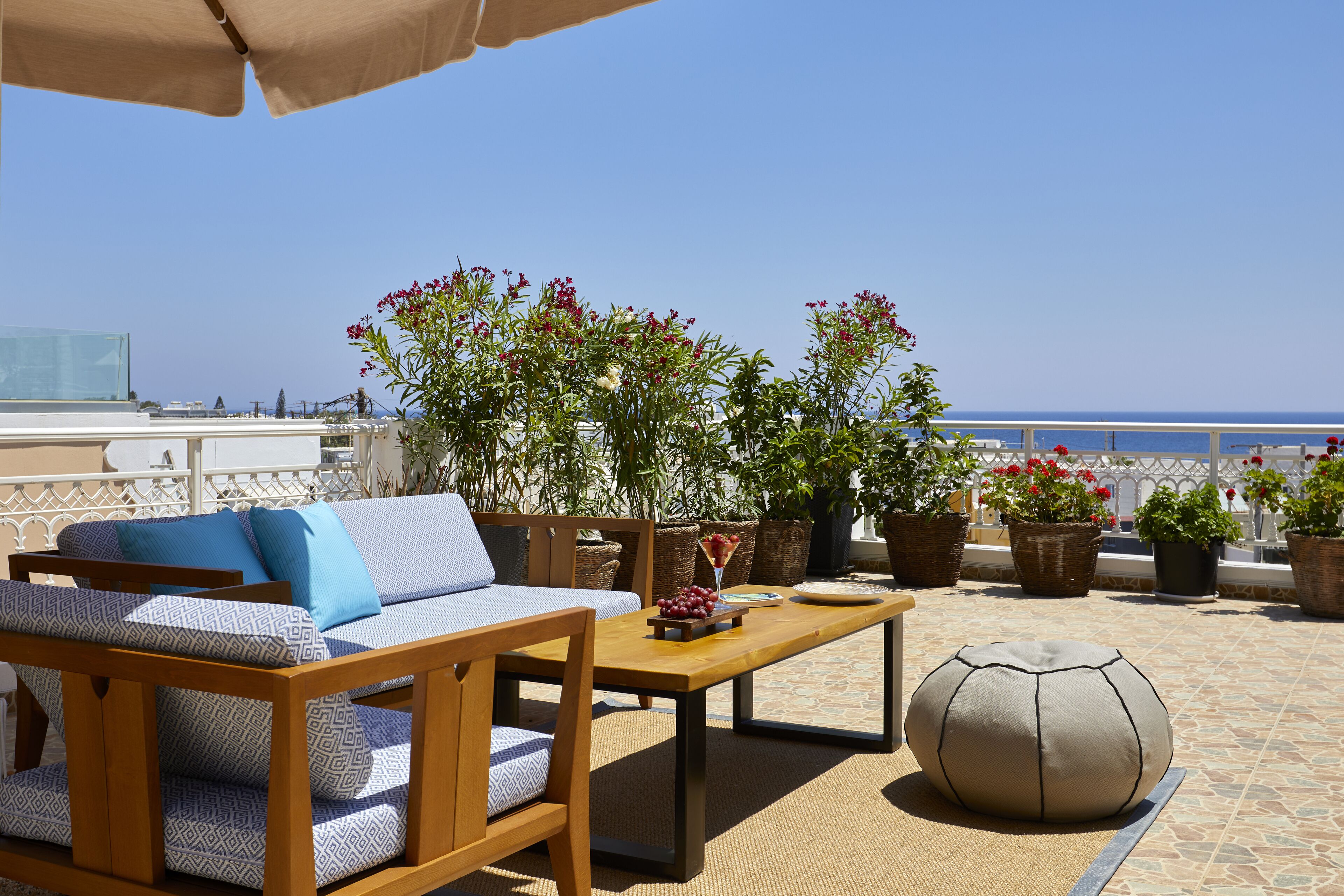 A terrace with a wooden sofa, a table, and potted plants.