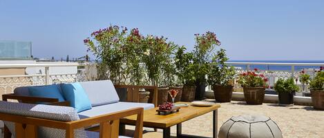 A terrace with a wooden sofa, a table, and potted plants.