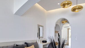 Una sala de estar moderna con un sofá gris, un florero blanco y un comedor al fondo.