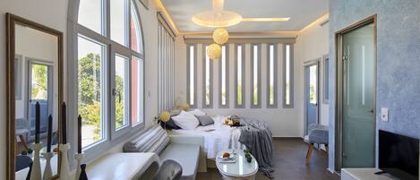 Een moderne slaapkamer met een groot bed, een zithoek en een televisie.