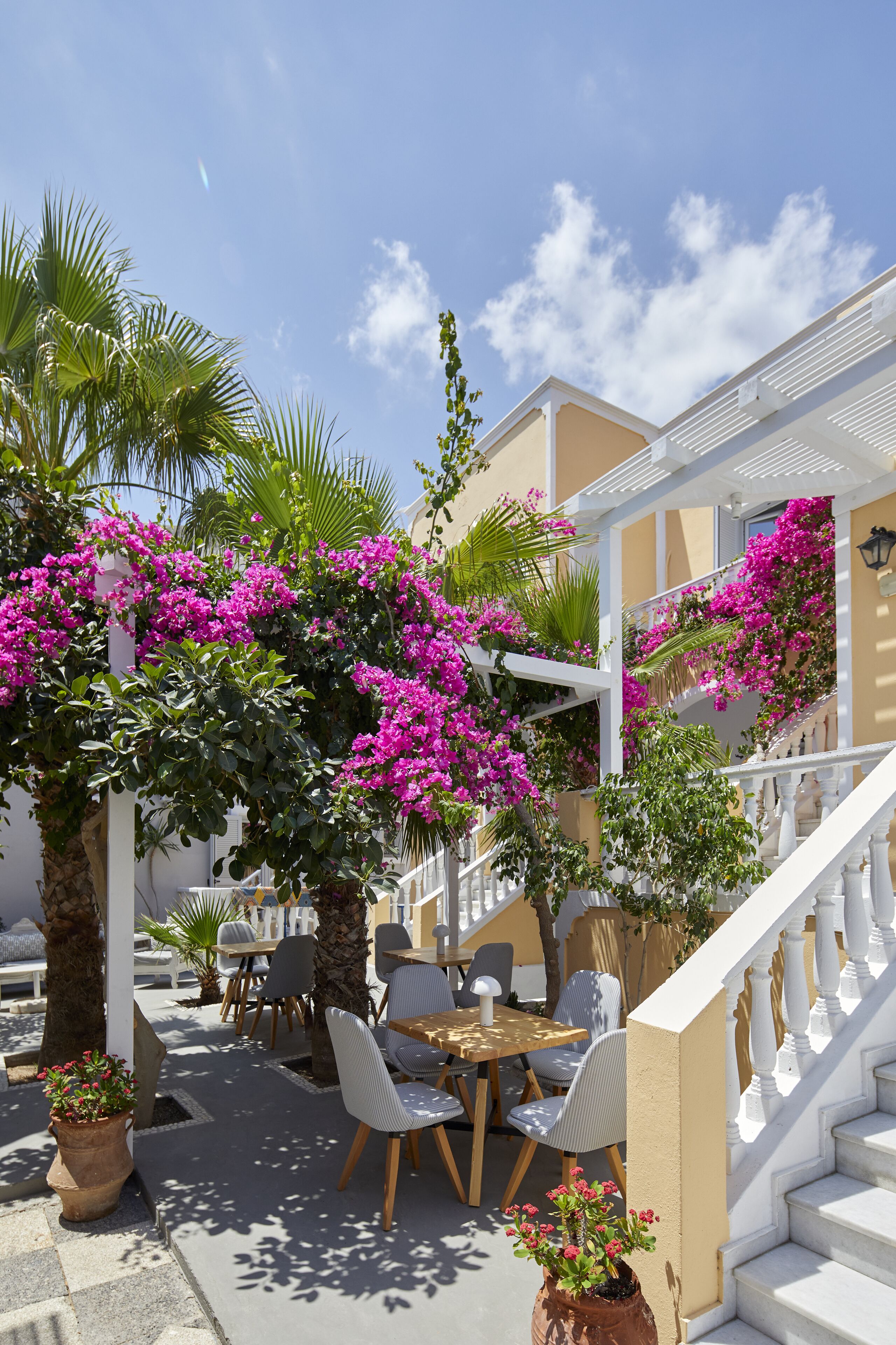 A terrace with outdoor seating, a staircase, and bougainvillea flowers.