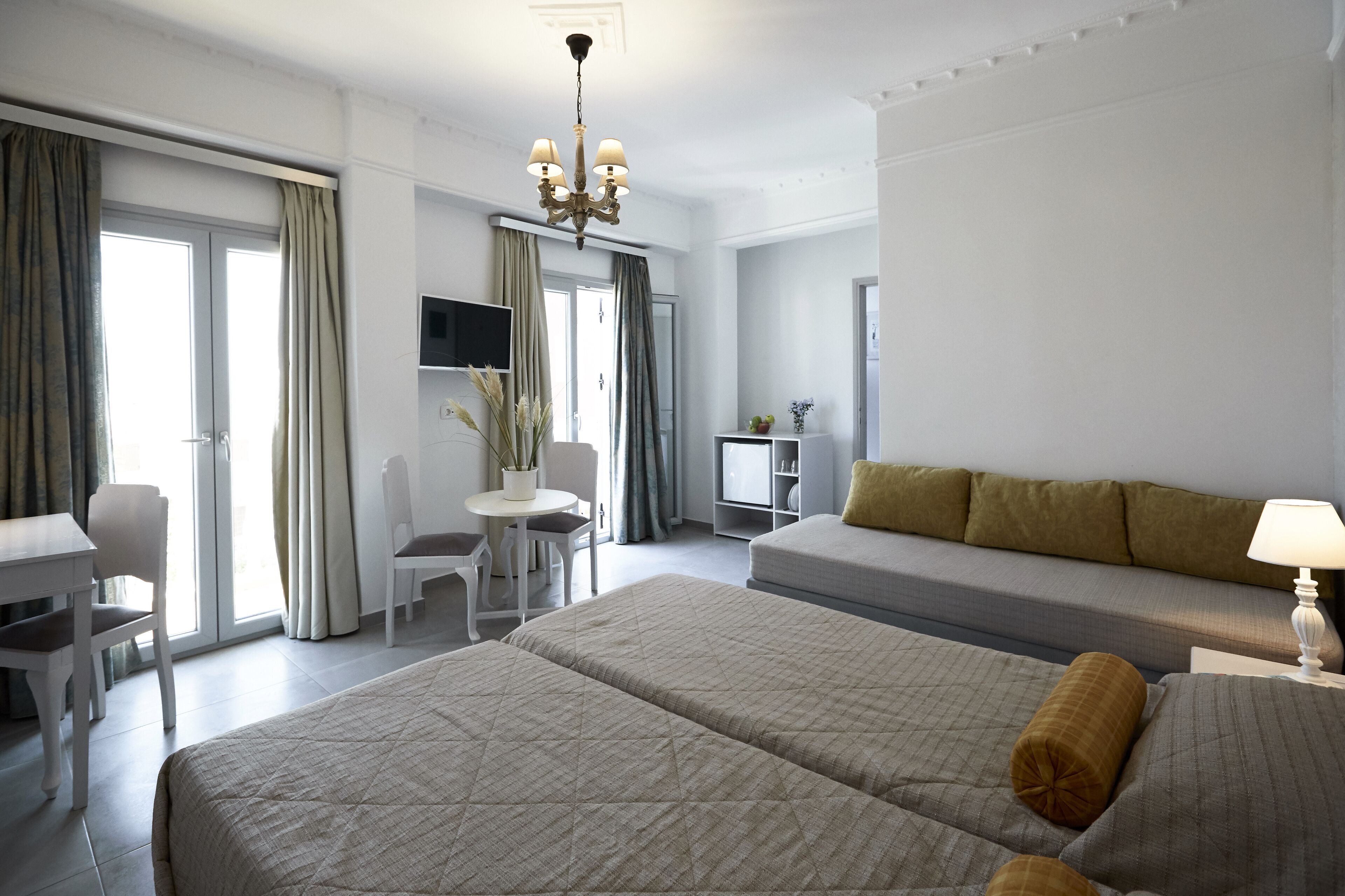 Habitación de hotel con dos camas, un escritorio, una silla, un televisor y un sofá.