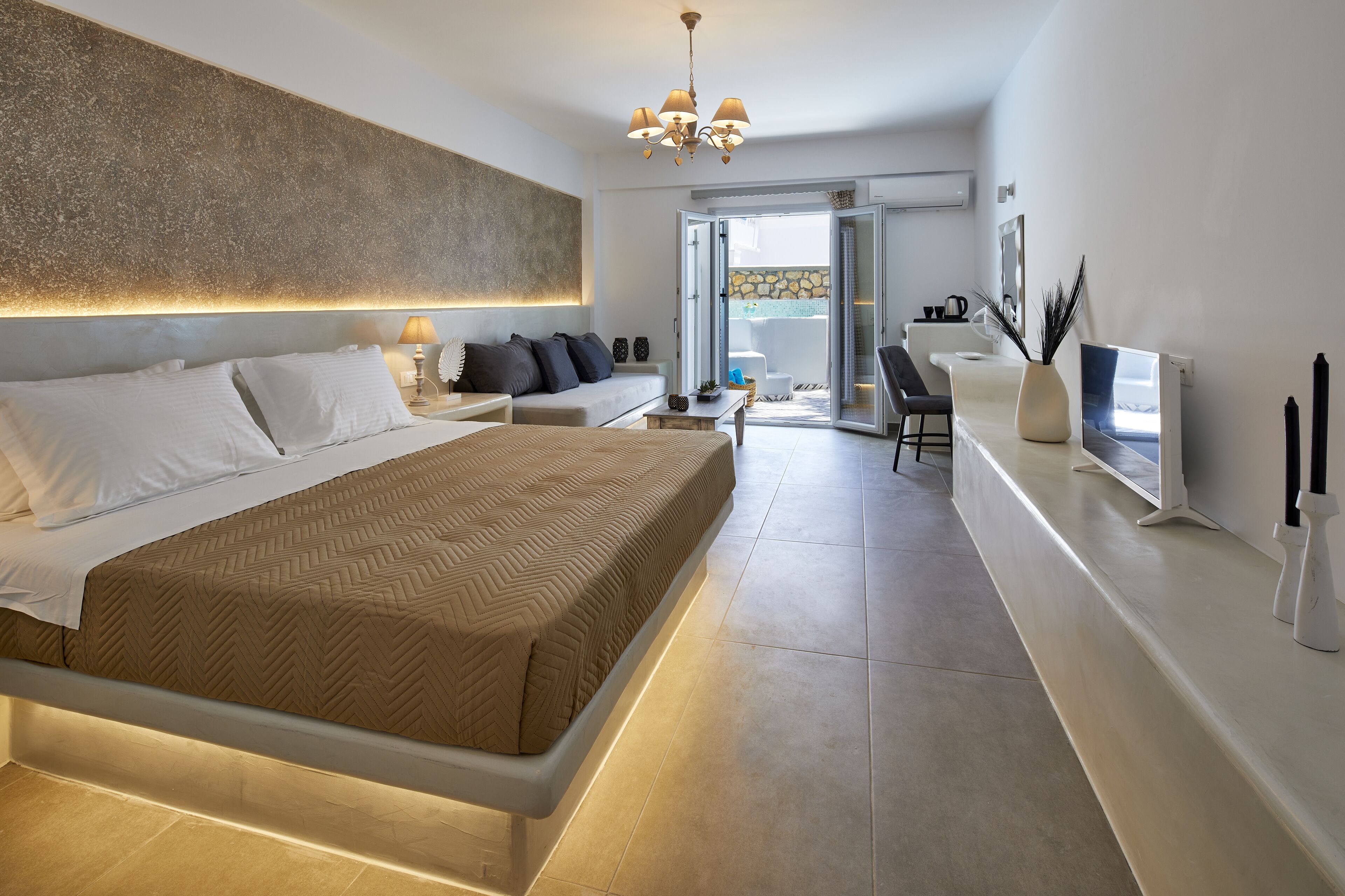 Un dormitorio moderno con una cama grande, mesitas de noche, un escritorio y vistas al exterior.