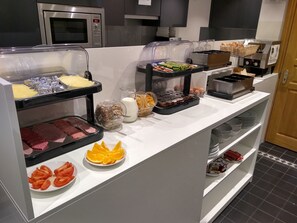 Ein Buffet mit verschiedenen Speisen, darunter Fleisch, Käse, Obst und Getränke.
