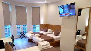 A hotel room with two beds, a TV, a desk, and a chair. - Mstay Russell Court Hotel (London)