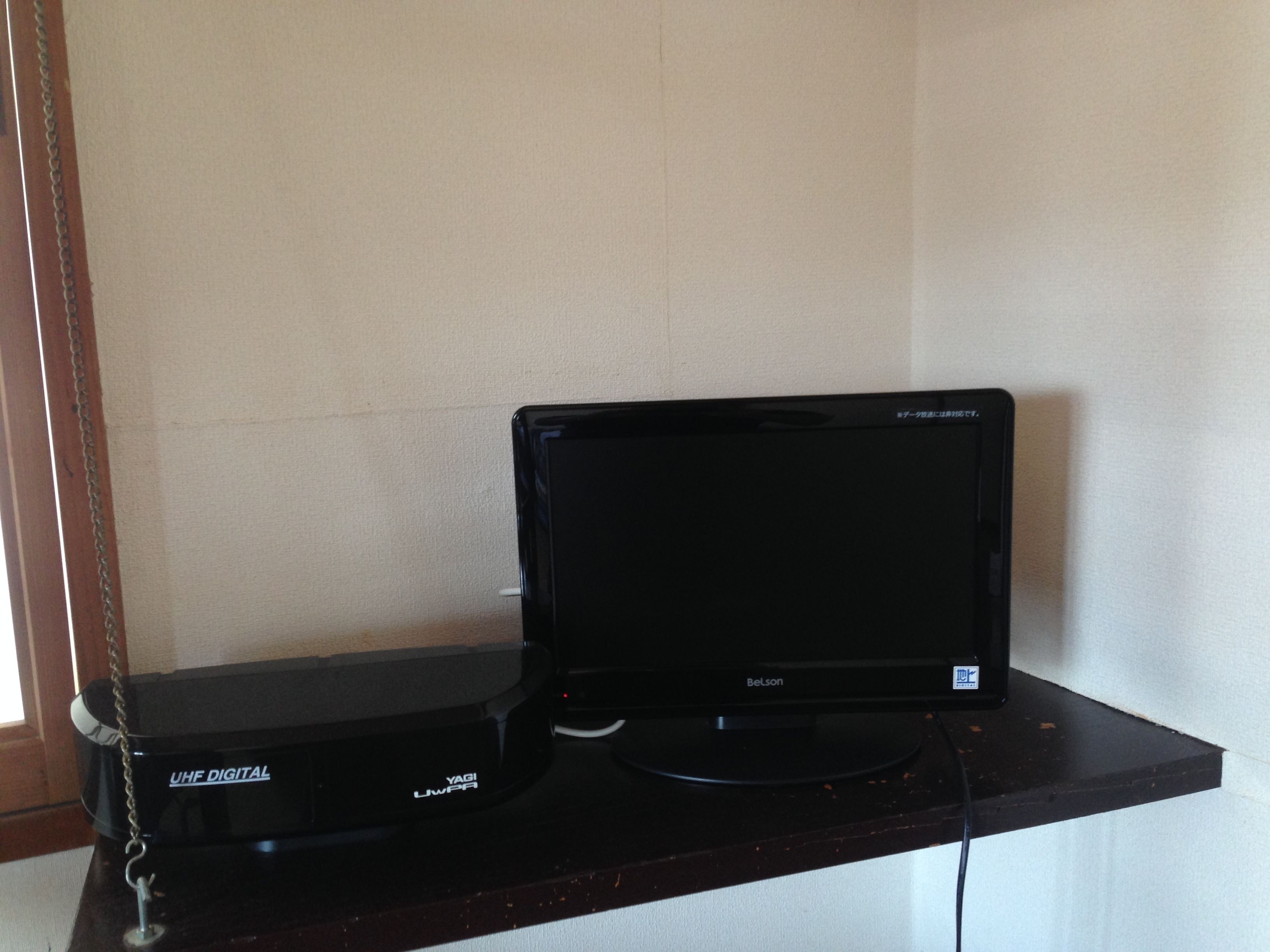 A black flat-screen TV on a black stand with a chain.