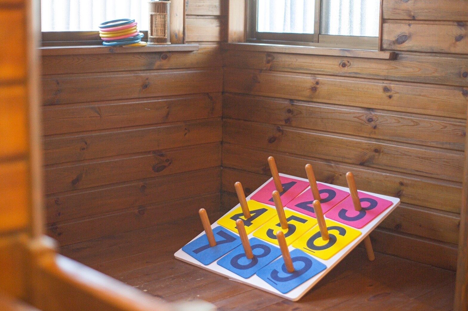 Interior de una cabaña de madera con una pequeña mesa que sostiene bloques numéricos y palitos de colores.