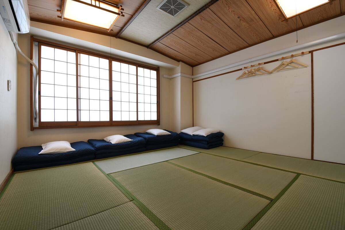 Een traditionele Japanse kamer met tatami matten, een laag houten plafond en een groot shoji-schermraam.