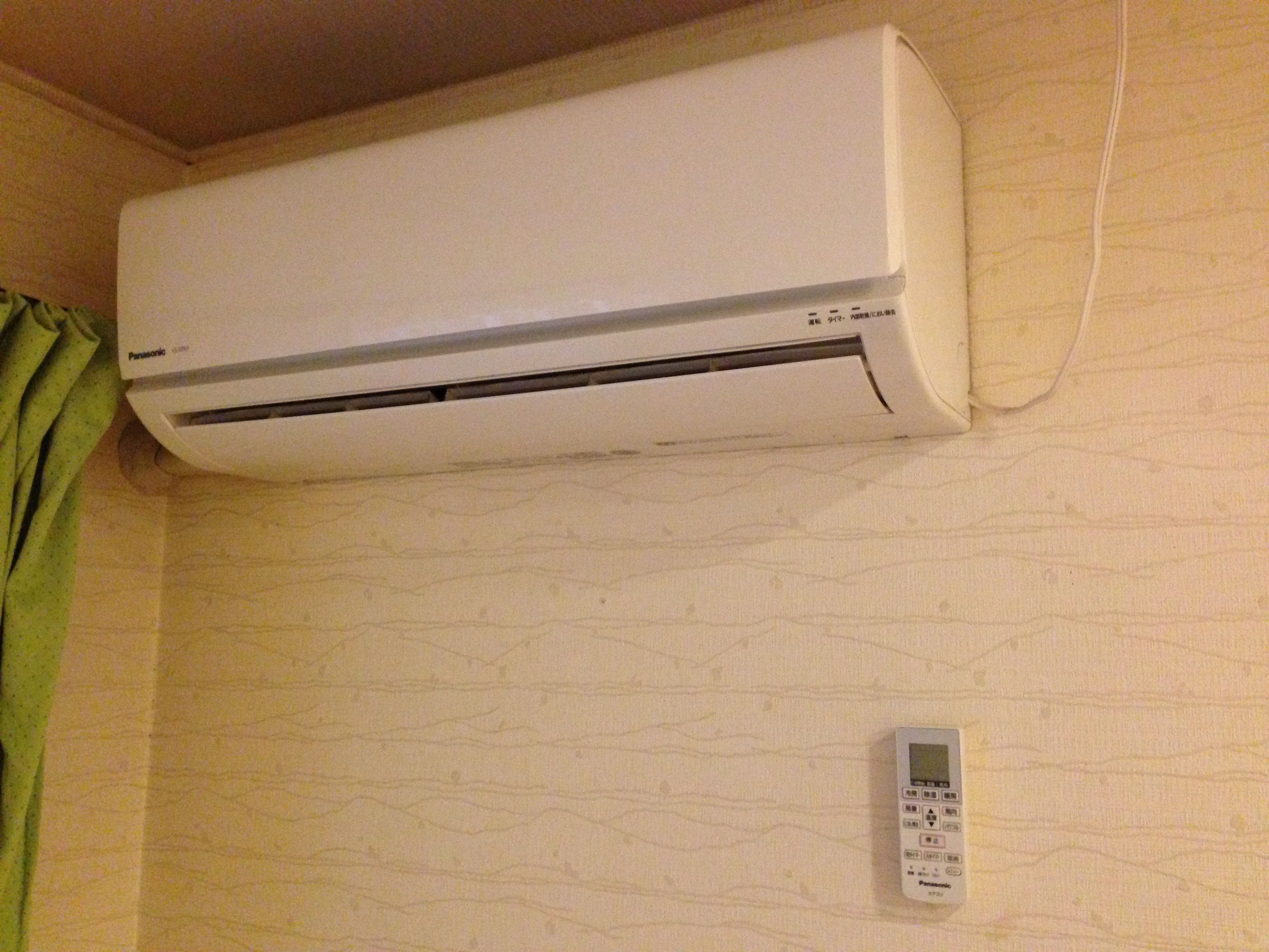 A white air conditioning unit mounted on a wall with a control panel below it.
