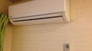 A white air conditioning unit mounted on a wall with a control panel below it.