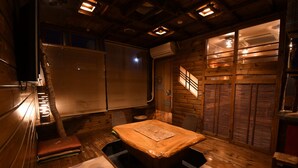 A traditional wooden room with a central table, benches, and a sliding door. - Onsen Yado Hamayu Nagi - Hostel (Beppu)