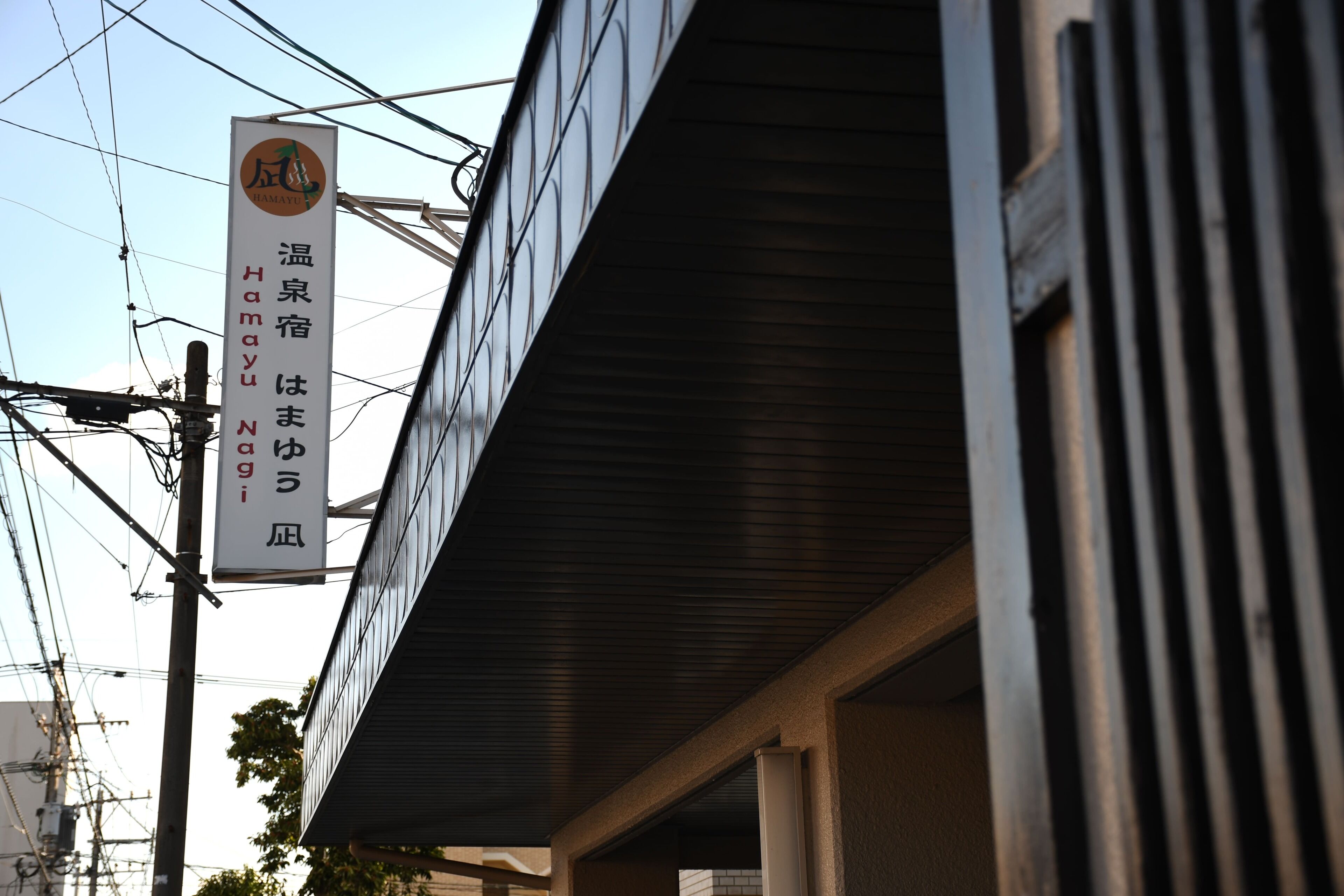 Ein Gebäude mit einem Schild, auf dem „温泉宿はまゆう風呂“ und „HAMAYU NAGI“ steht.