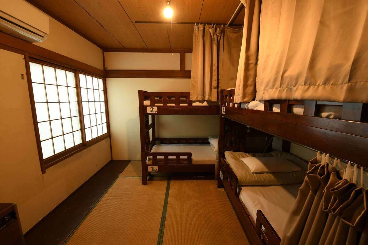 Een traditionele Japanse kamer met tatami vloerbedekking, een futonbed en shoji schuifdeuren.