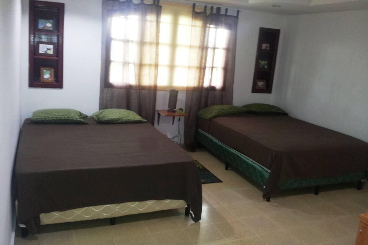 A room with two single beds, a small table, and a window with curtains.