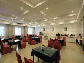 Un vaste espace de restauration dans l’hôtel, avec de nombreuses tables et chaises, un comptoir central et des œuvres d’art encadrées accrochées aux murs.