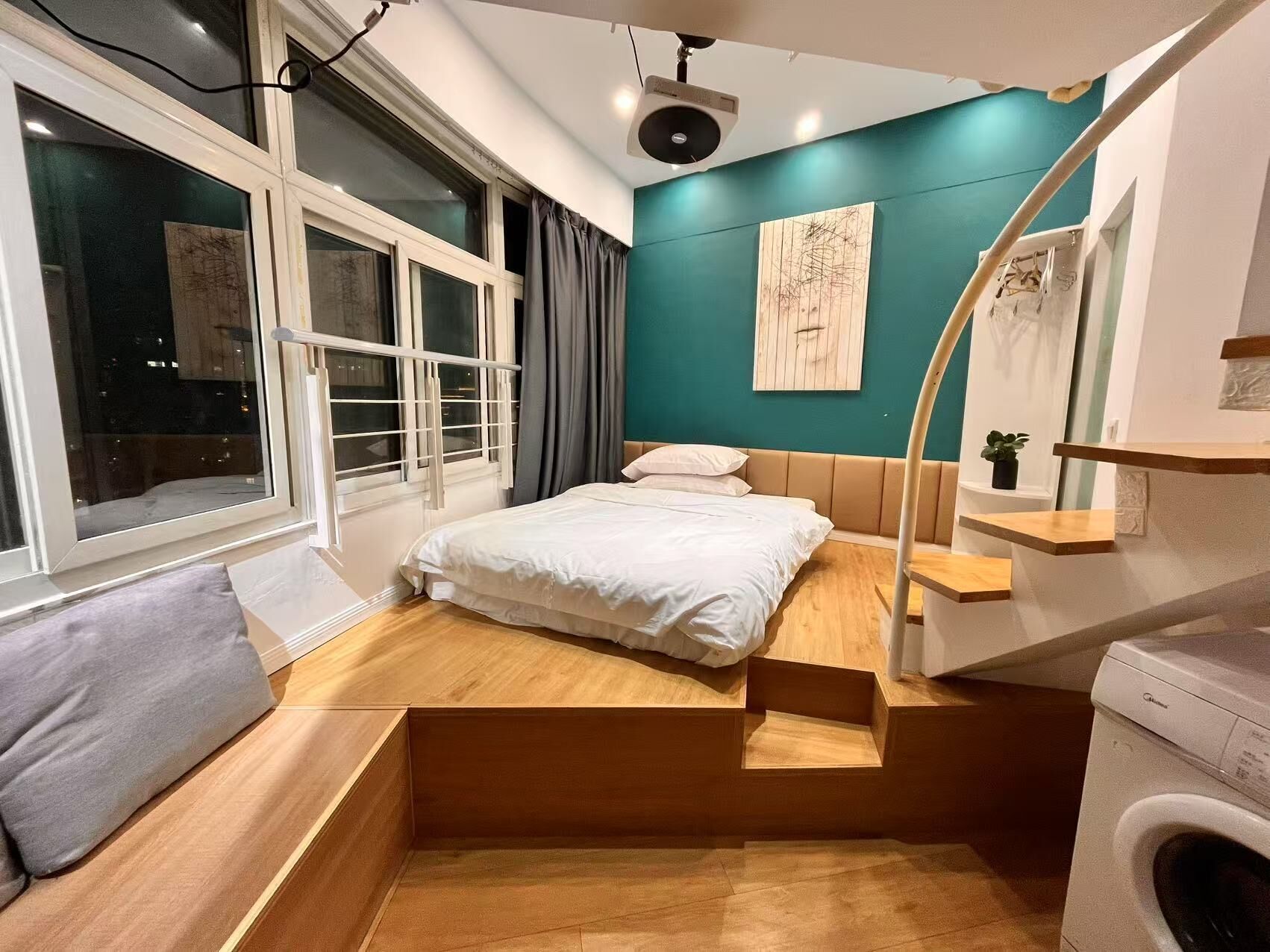 A compact bedroom with a bed, a washing machine, and a window with curtains.
