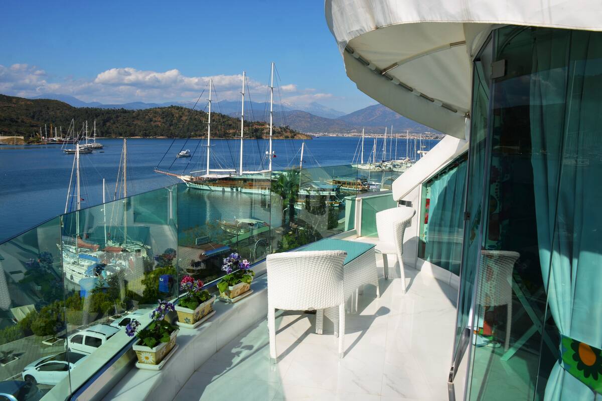 A balcony with a glass railing overlooking a marina with sailboats.