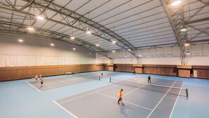An indoor tennis court with a high ceiling and metal beams.