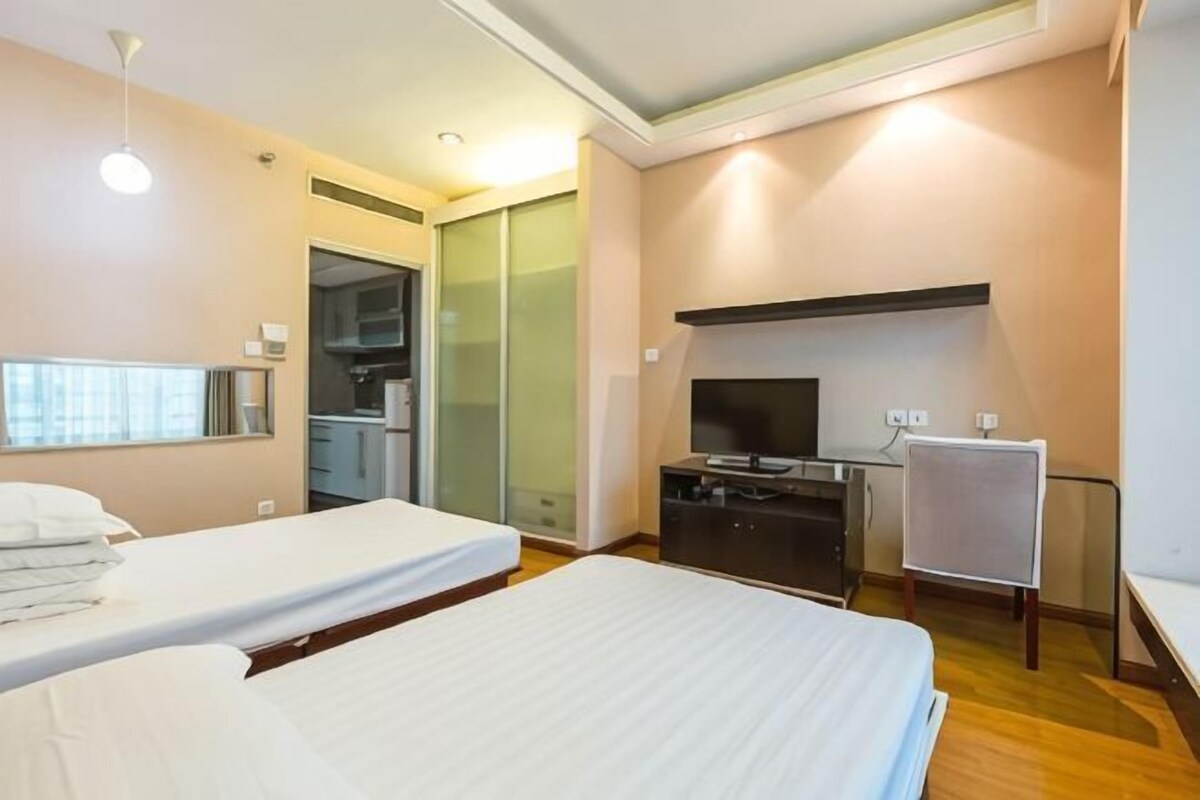 A hotel room with two beds, a TV, a desk, and a wardrobe.