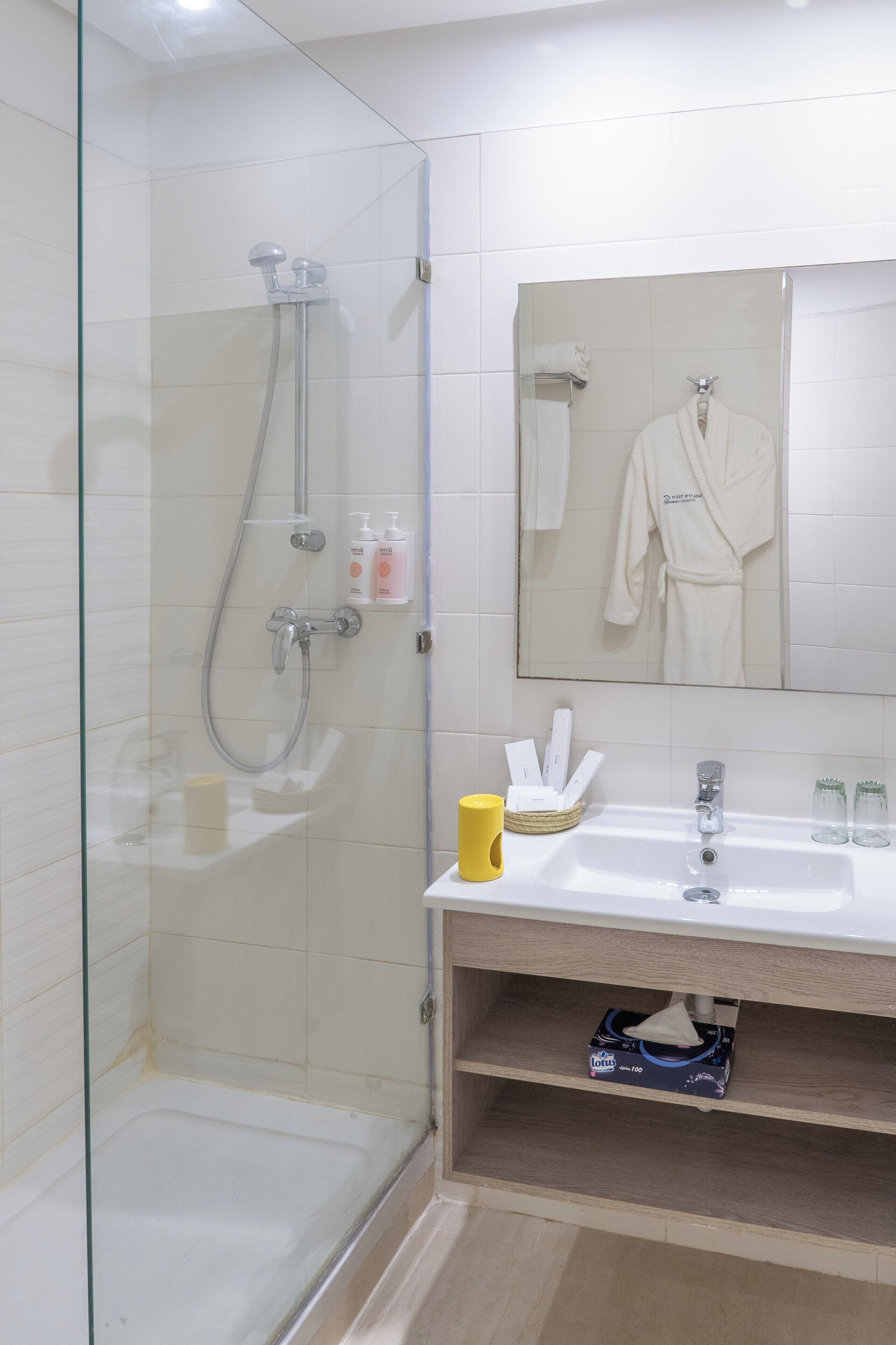 A modern bathroom with a glass-enclosed shower, a sink with toiletries, and a mirror above the sink.