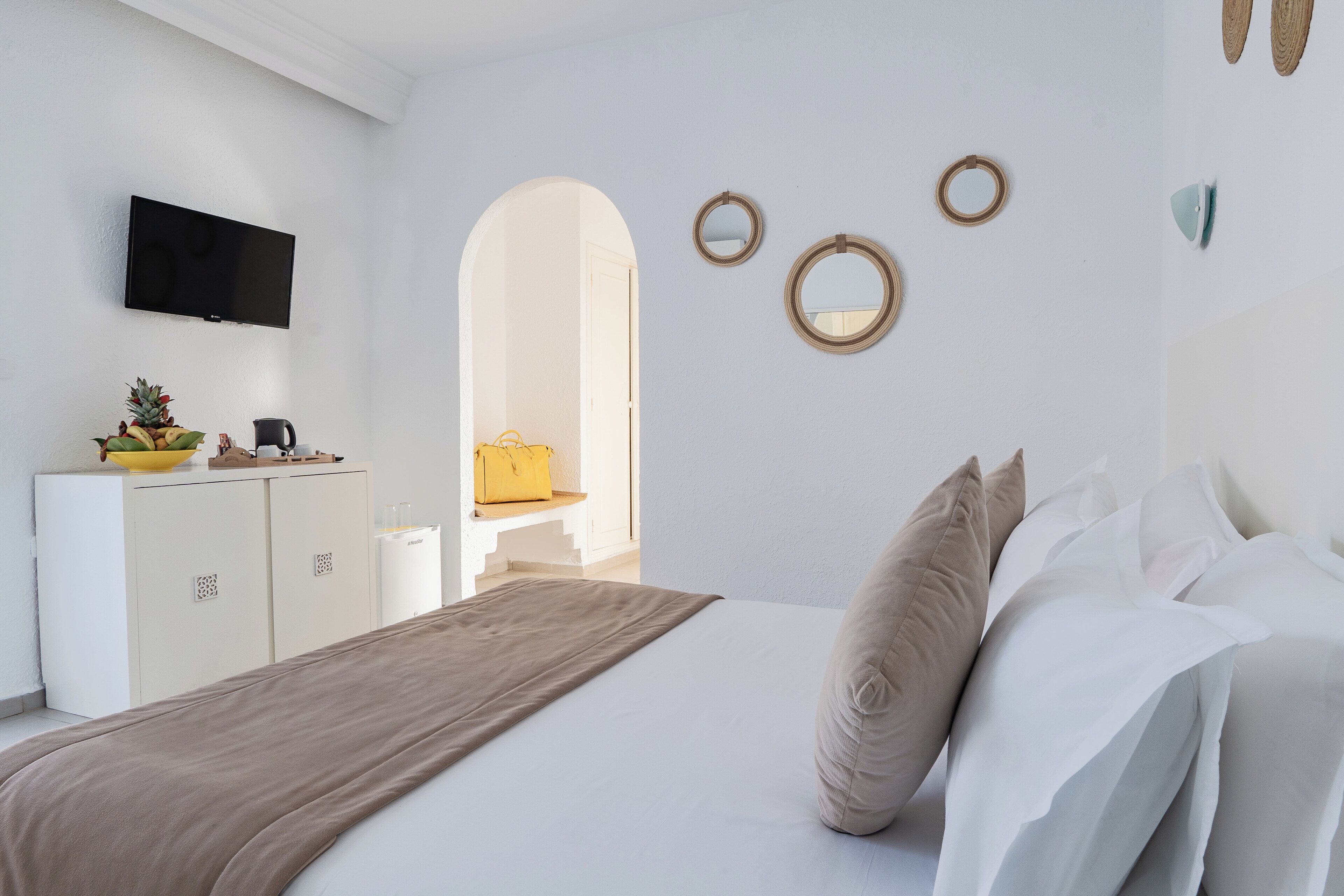 Una camera da letto con un letto, una TV a muro, un armadio e uno specchio.