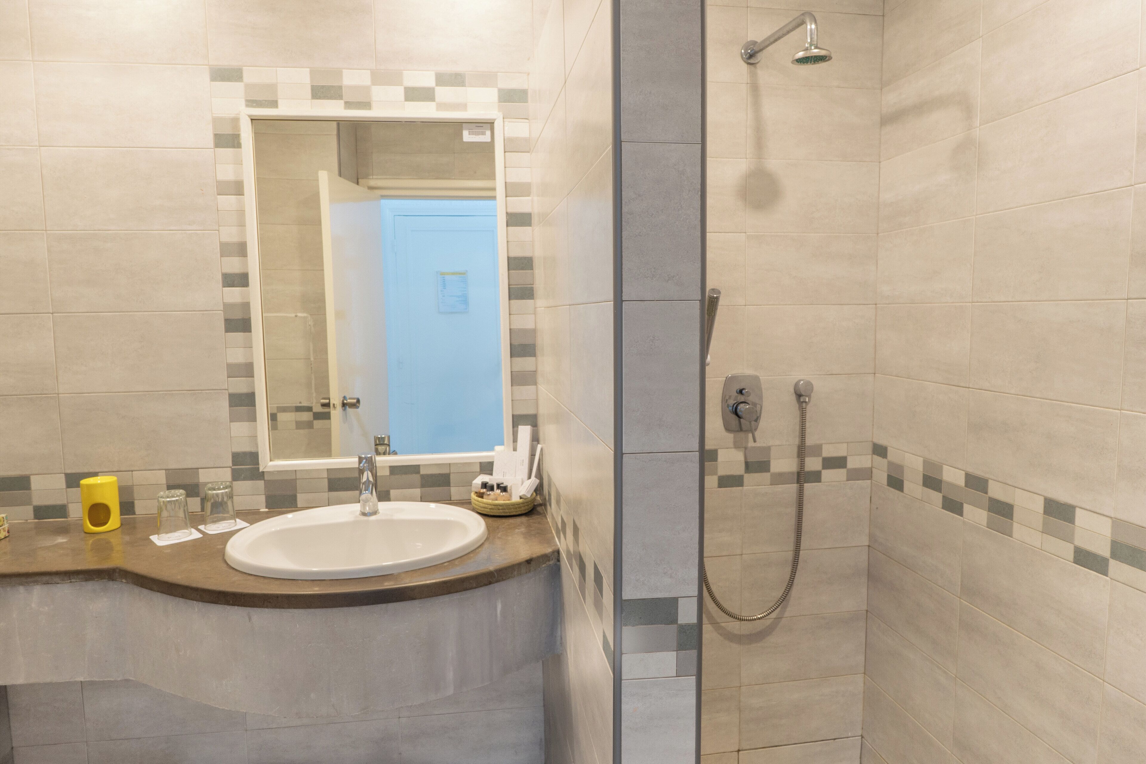 A bathroom with a sink, mirror, and shower.