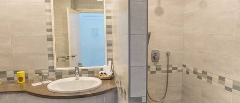 A bathroom with a sink, mirror, and shower.