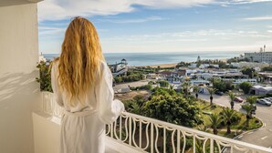 Un balcón con vista a la costa, con edificios, vegetación y cielo despejado.