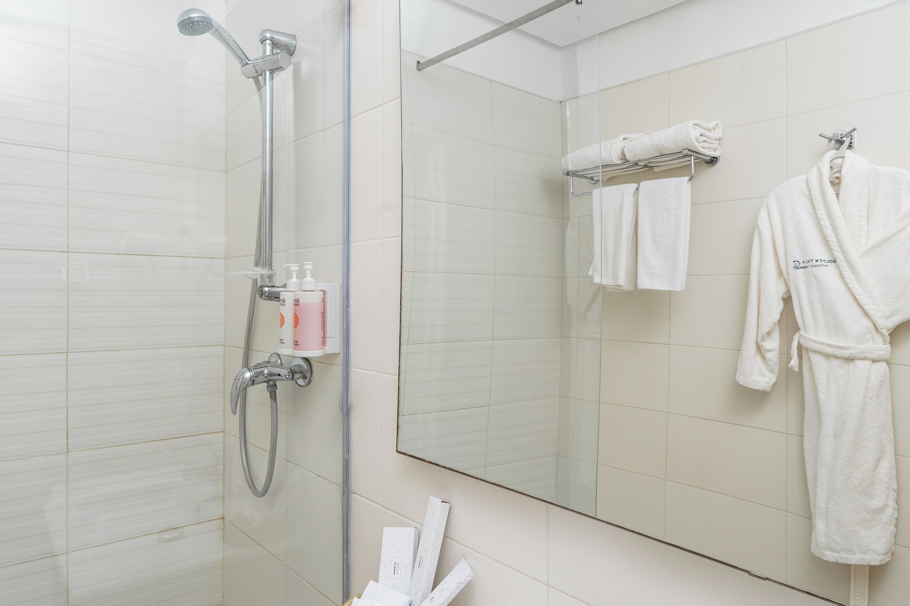 Ein modernes Badezimmer mit Dusche, Handtuchhalter mit Handtüchern und einem Bademantel an der Wand.