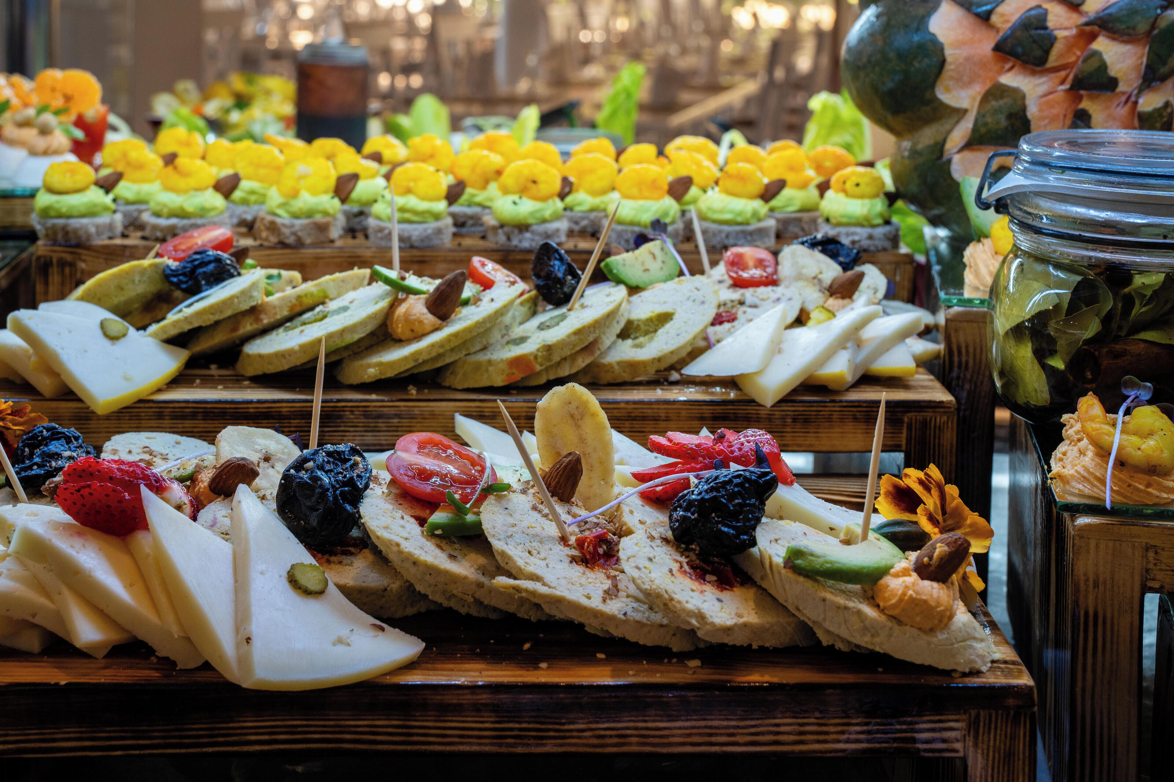 A variety of food items arranged on wooden boards, including sandwiches, fruits, and nuts.
