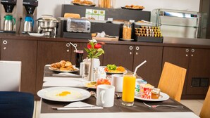 Un bufé de desayuno con diversas opciones de comida, una máquina de café y un dispensador de jugo.