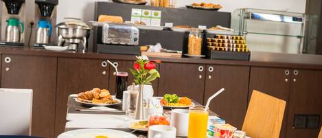 Un buffet de petit-déjeuner proposant une variété d’aliments, une machine à café et un distributeur de jus.