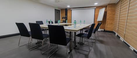 A conference room with a long table, black chairs, and water bottles.