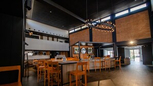 Un restaurante espacioso con techos altos, una barra central y diversas opciones de asientos.