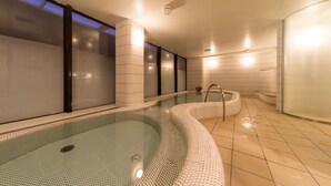 A modern indoor swimming pool with a glass wall, tiled walls, and a curved design. - Hotel Resol Trinity Sapporo (Sapporo)