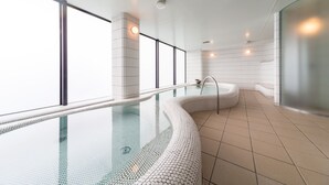 A modern indoor swimming pool with a glass bottom, a jacuzzi, and a view of the city through large windows. - Hotel Resol Trinity Sapporo (Sapporo)