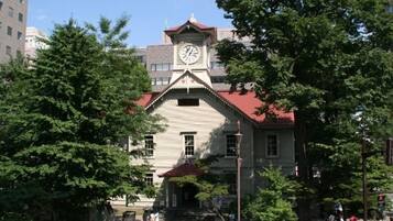 A historic building with a clock tower, surrounded by trees and a pedestrian area.