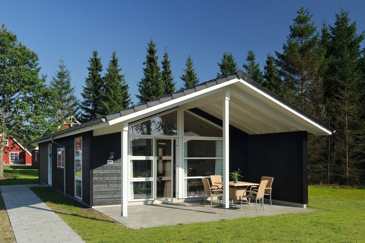 A modern house with a covered patio, large windows, and a small garden area.