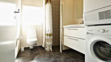Un baño pequeño con inodoro, cortina de ducha, lavadora y lavamanos.