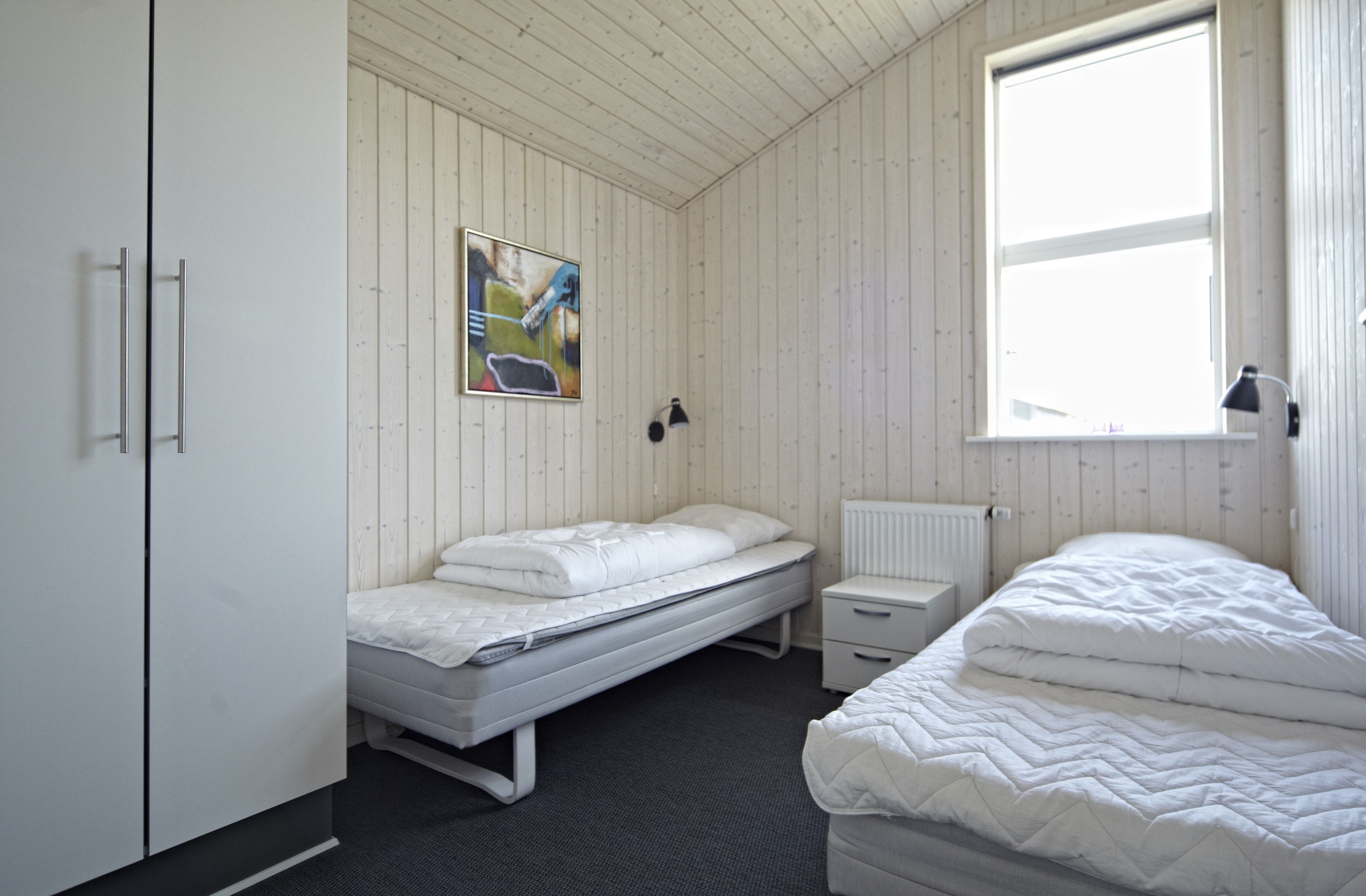 Ein Zimmer mit einem Einzelbett, einem Nachttisch, einer Heizung und einem Fenster.