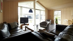 A modern living room with a large TV, leather sofas, a coffee table, and a chair. - Lalandia Resort Billund (Billund)