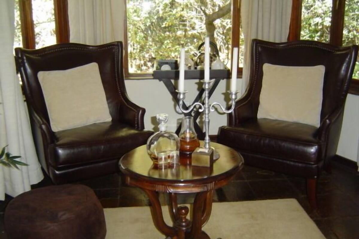 A room with two leather armchairs, a small round table with a glass top, and a candle holder.