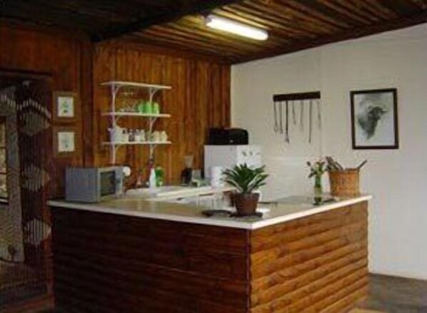A rustic kitchen with wooden cabinetry, a countertop, and a hanging light fixture. - Forest Creek Lodge & Spa (Mashishing)